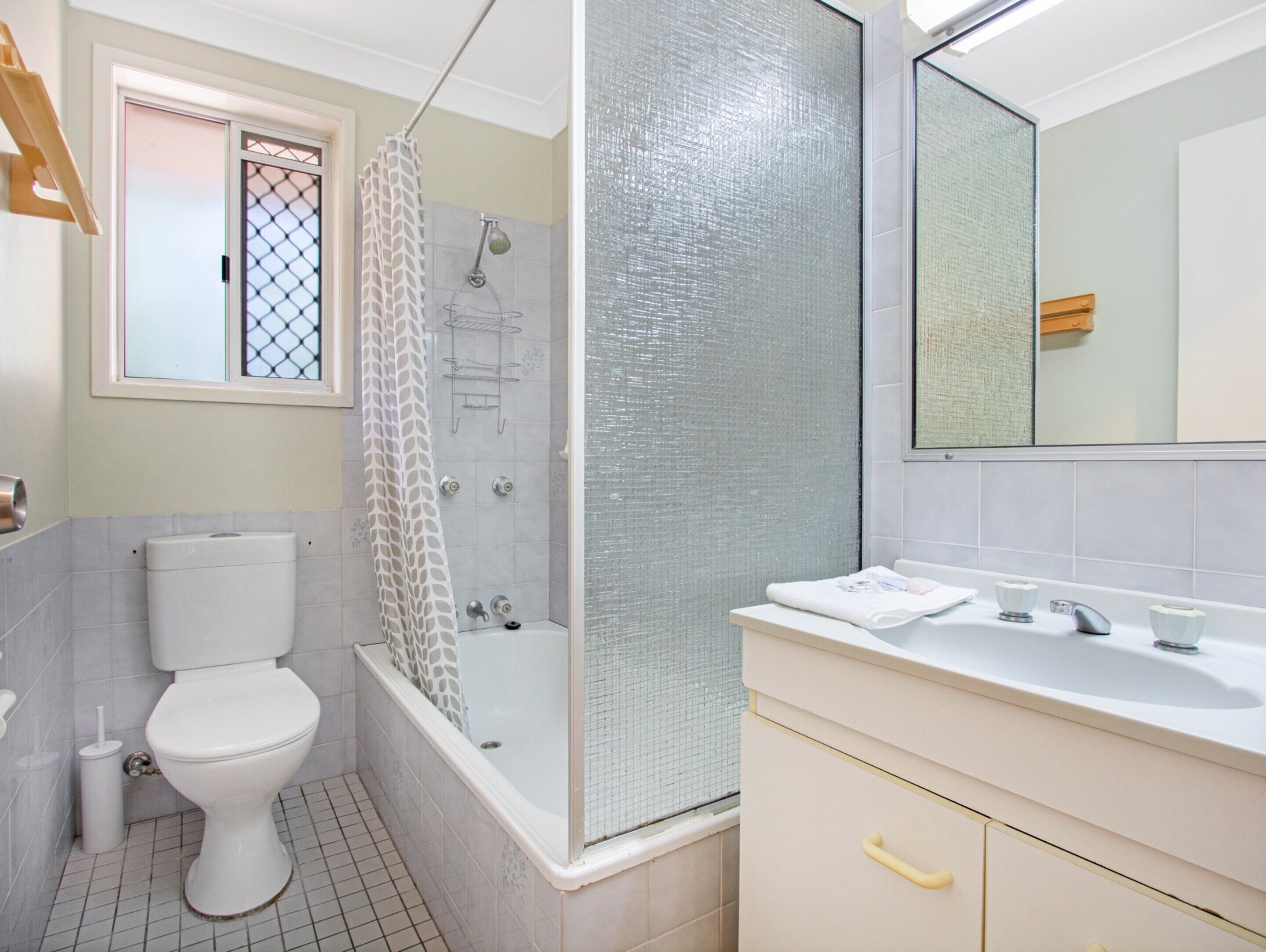Une salle de bain avec des toilettes, une douche et un lavabo.