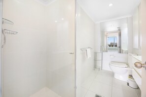 Un baño moderno con cabina de ducha de vidrio, inodoro y lavamanos.