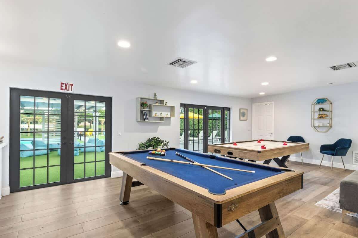 A pool table with a blue felt surface, a second pool table, and an exit sign.