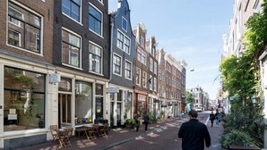 A street with buildings, a sidewalk, and a few people walking. - Twenty Five Garden (Room 2) (Amsterdam)