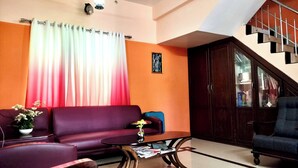 Una sala de estar con un sofá morado, una mesita con un jarrón y una escalera con barandilla.