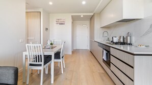 A modern kitchen with white cabinets, a built-in oven, and a stainless steel sink. - City Views & Inner-north Cool at Your Door (Melbourne)