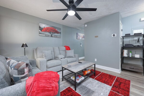A modern living room with a grey sofa, a coffee table, and a red rug.