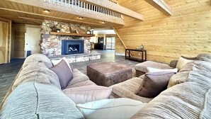 A spacious living area with a stone fireplace, wooden ceiling, and a cozy seating arrangement. - Family Cabin w/Hot Tub | Red Rock Views | Pets (Kanab)