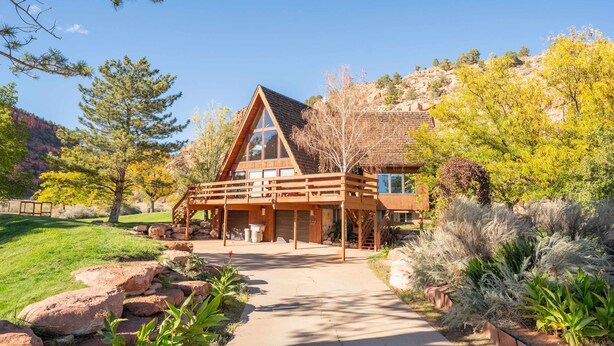 A wooden cabin with a triangular roof, a covered porch, and a stone pathway leading to the entrance. - Family Cabin w/Hot Tub | Red Rock Views | Pets (Kanab)