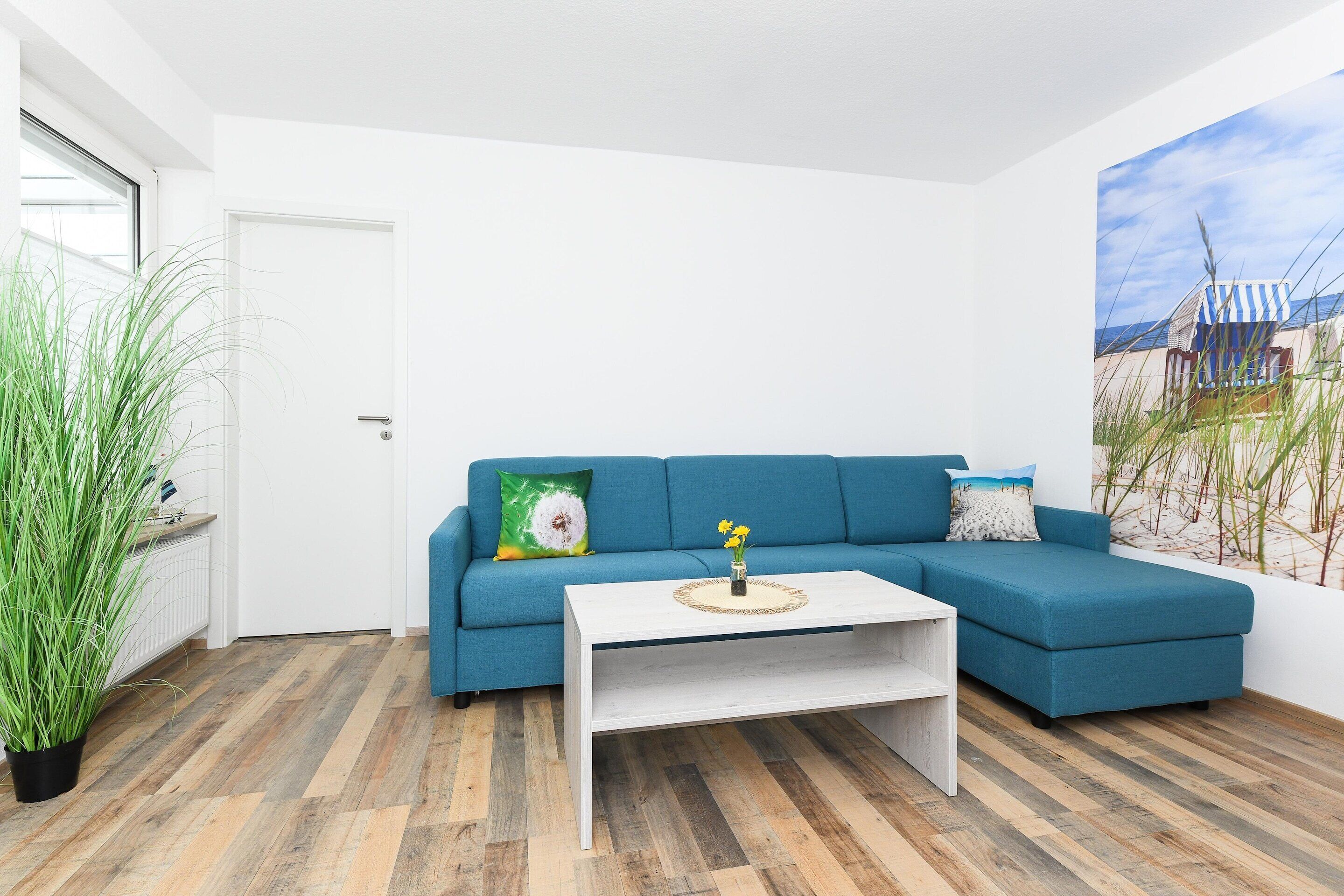 A modern living room with a blue sofa, white coffee table, and a large window.