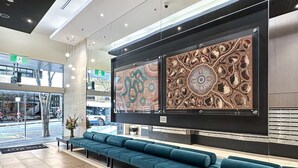 A modern lobby with a seating area, large windows, and artwork on the walls.