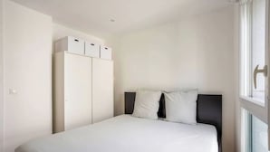 Un dormitorio con cama, armario y ventana.