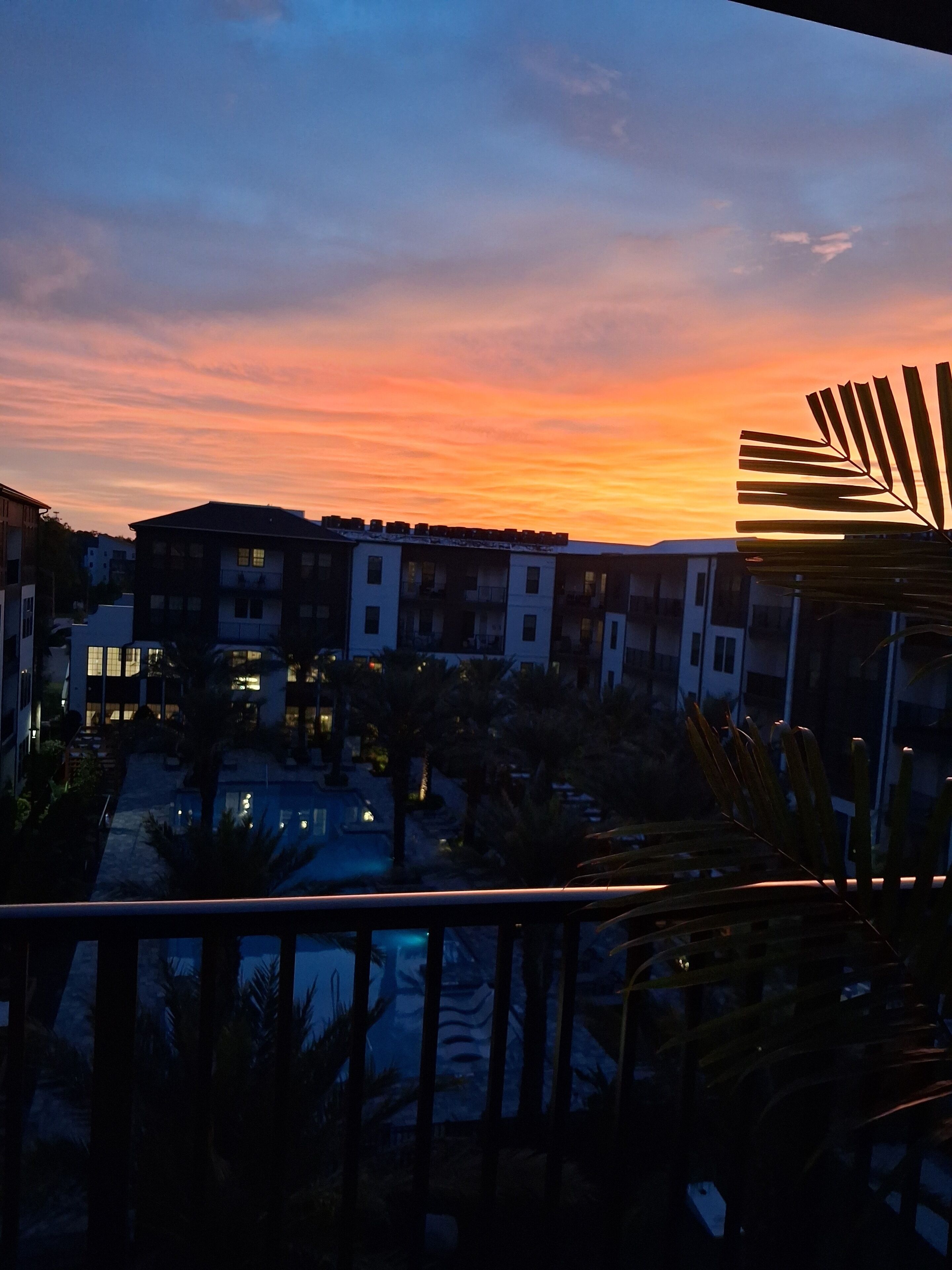 A view of a residential area with buildings and a pool during sunset.