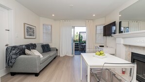 Una sala moderna con un sofá gris, una mesa de comedor blanca y una chimenea.