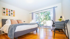 A modern bedroom with a bed, a desk, and a view of the outdoors. - Central 3BR Home - Steps from Mountain View DT, Castro St (Mountain View)