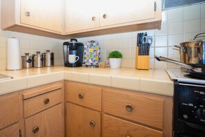 A kitchen with wooden cabinets, a coffee maker, a kettle, a plant, and a dishwasher. - Central 3BR Home - Steps from Mountain View DT, Castro St (Mountain View)