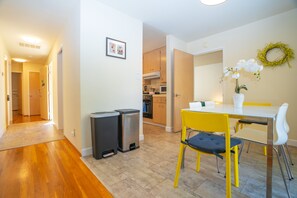 A kitchen with wooden cabinets, a microwave, and a dining area with a yellow table and chairs. - Central 3BR Home - Steps from Mountain View DT, Castro St (Mountain View)