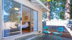 A room with a bed, a window, and a sliding door. There is a small table and two chairs outside. - Central 3BR Home - Steps from Mountain View DT, Castro St (Mountain View)