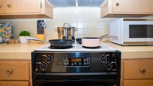 A kitchen with a stove, pots, a microwave, and wooden cabinets. - Central 3BR Home - Steps from Mountain View DT, Castro St (Mountain View)