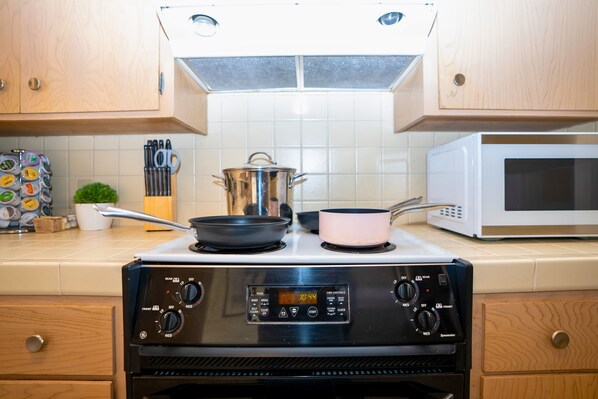 A kitchen with a stove, pots, a microwave, and wooden cabinets. - Central 3BR Home - Steps from Mountain View DT, Castro St (Mountain View)