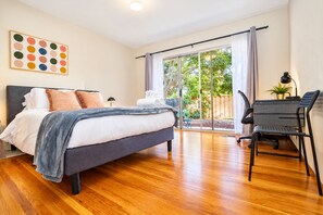 A modern bedroom with a bed, a desk, and a view of the outdoors. - Central 3BR Home - Steps from Mountain View DT, Castro St (Mountain View)