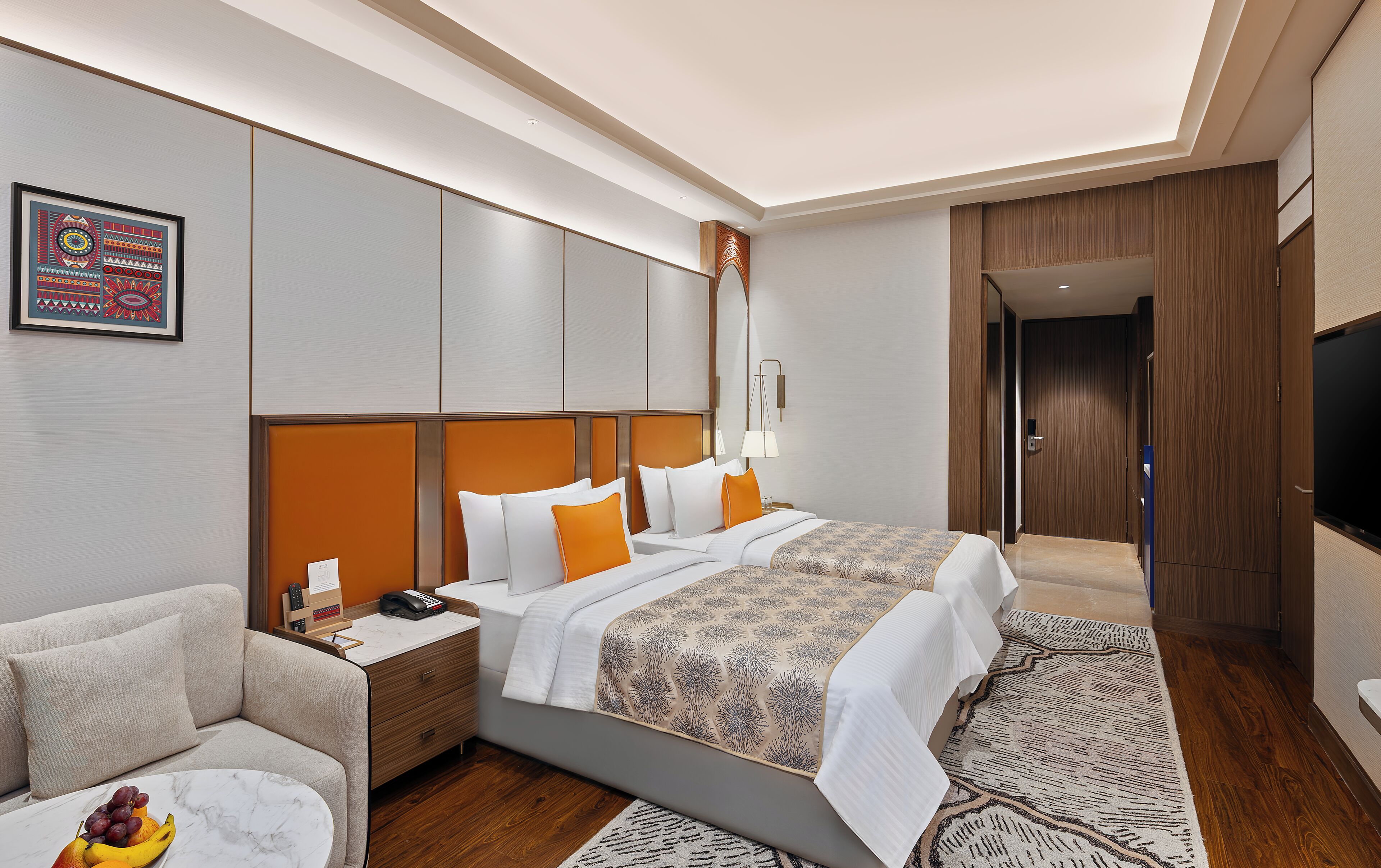 Habitación de hotel con una cama grande, un sofá, un escritorio con teléfono y un frutero.