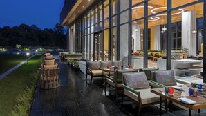 A modern outdoor seating area with wicker furniture and a view of the interior. - Fortune Select Siliguri - Member ITC Hotels' Group (Jalpaiguri)