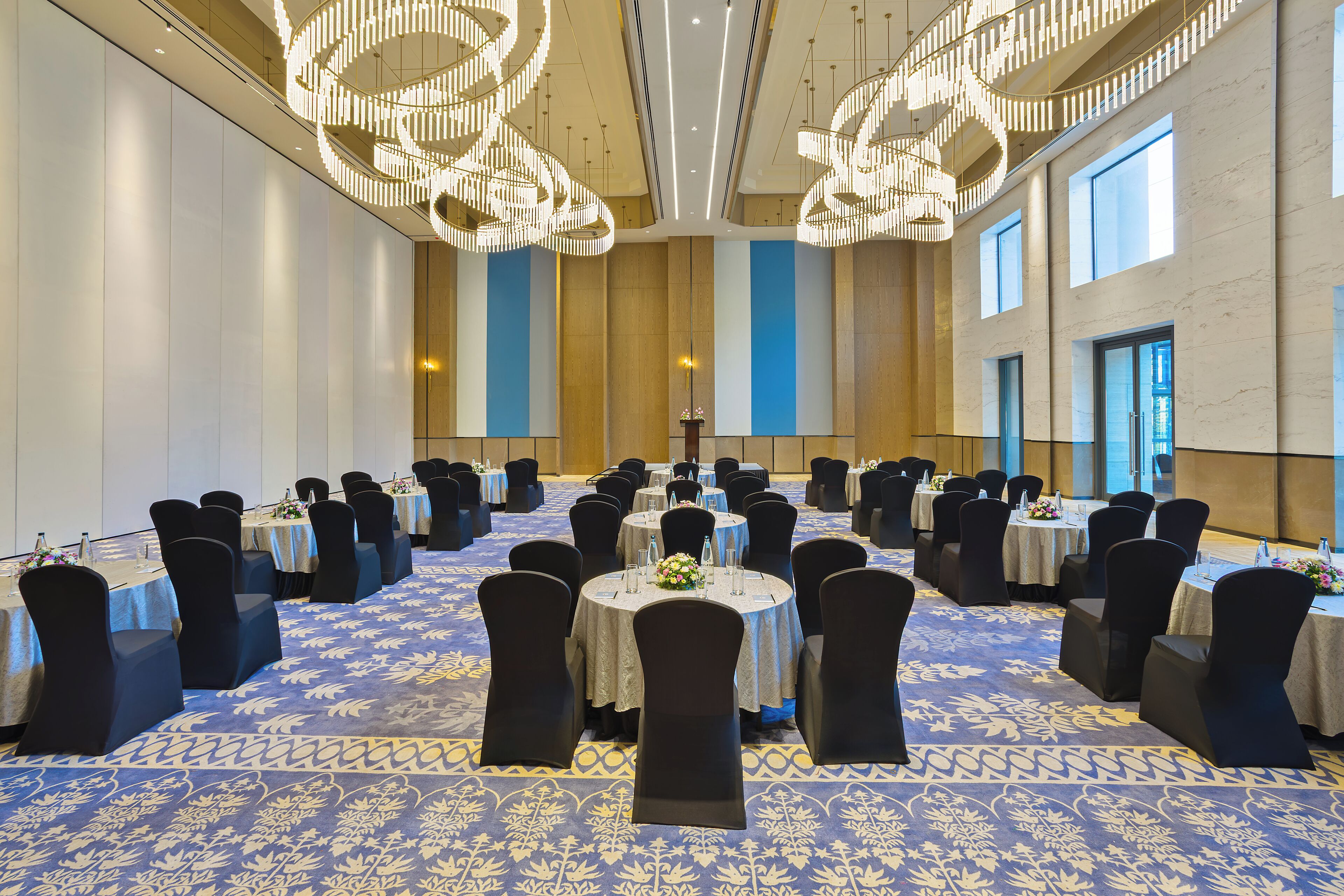 A conference room with round tables, black chairs, and a patterned carpet.