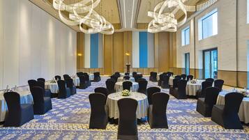 A conference room with round tables, black chairs, and a patterned carpet.