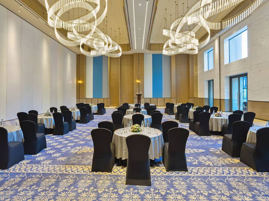 A conference room with round tables, black chairs, and a patterned carpet.