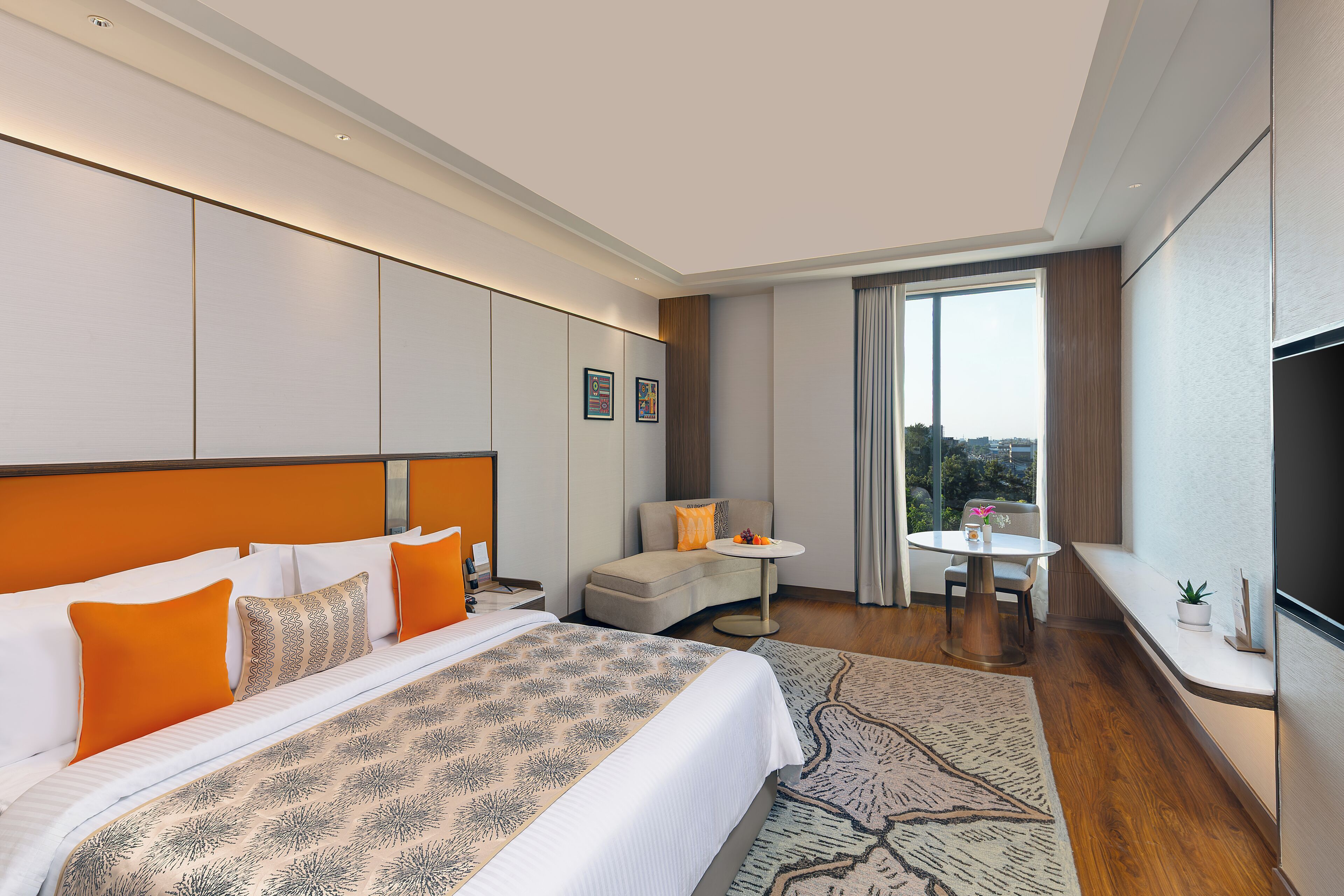 Een hotelkamer met een groot bed, een bank, een kleine tafel, een televisie en een raam met uitzicht.