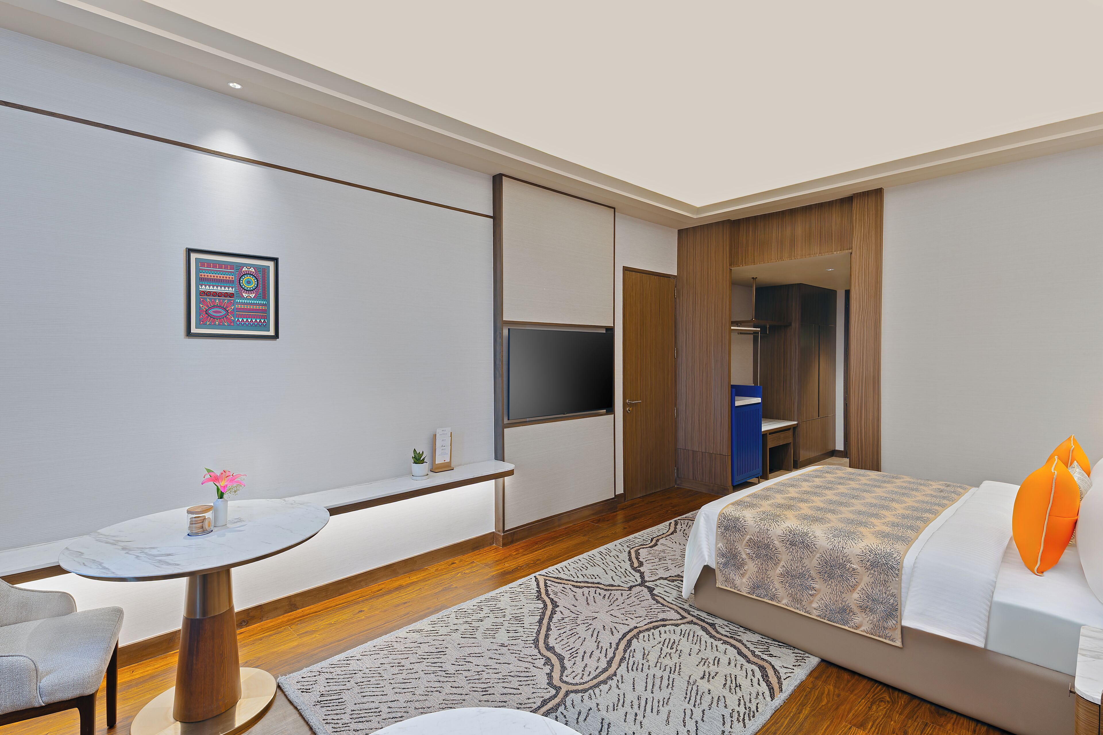 Een moderne hotelkamer met een bed, een bureau, een stoel, een televisie en een kledingkast.