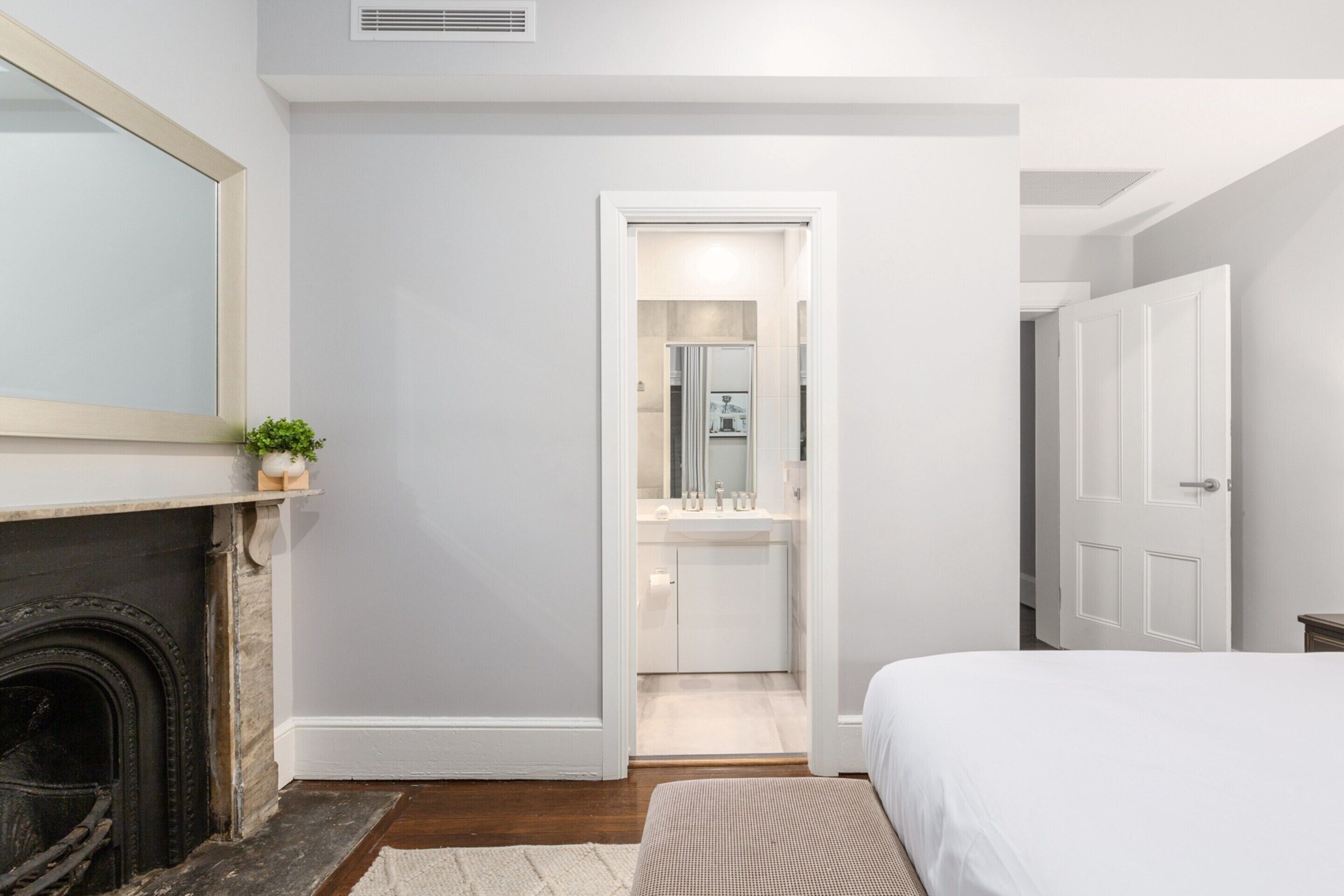 Un dormitorio con cama, chimenea y baño visible a través de una puerta abierta.
