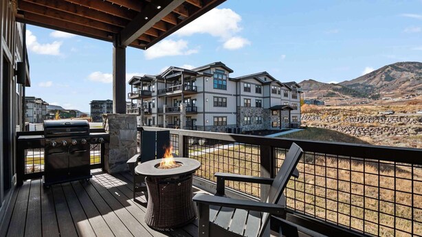 Un patio in legno con una griglia, un braciere e vista su un edificio a più piani con balconi.