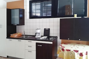 Una cocina con cafetera, lavamanos y armarios.