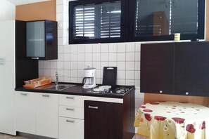 Eine Küche mit Kaffeemaschine, Spüle und Schränken.