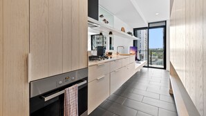 A modern kitchen with a built-in oven, a stainless steel range, and a large island with a sink. - Chic City Escape With Pool, Gym & Parking (Melbourne)