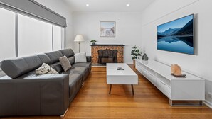 A modern living room with a leather sofa, a white coffee table, and a fireplace. - Spacious 3-bed With Outdoor Dining Near Airport (Melbourne)