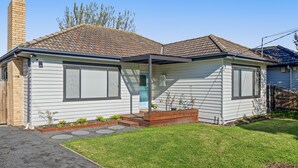 A single-story house with a front porch, a chimney, and a small garden area with stepping stones. - Spacious 3-bed With Outdoor Dining Near Airport (Melbourne)