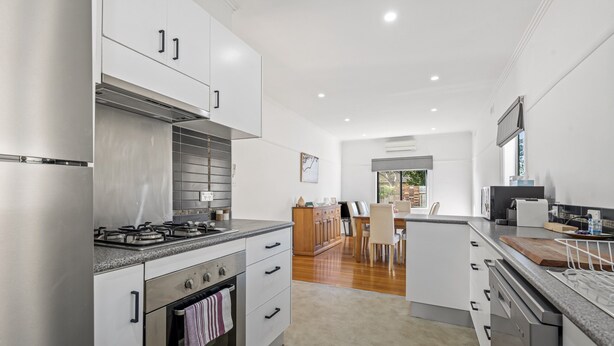 A modern kitchen with stainless steel appliances, wooden cabinets, and a central island with seating. - Spacious 3-bed With Outdoor Dining Near Airport (Melbourne)