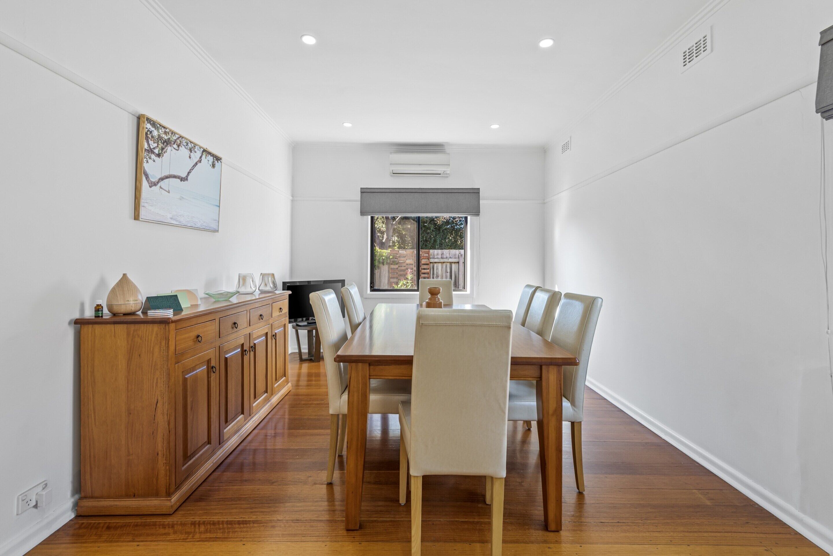 A dining area with a wooden table and chairs, a wooden cabinet, and a painting on the wall.