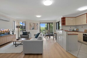 A modern apartment with a living room, dining area, kitchen, and balcony. - Comfy 2-bedroom Family Apartment With Free Parking (Brisbane)