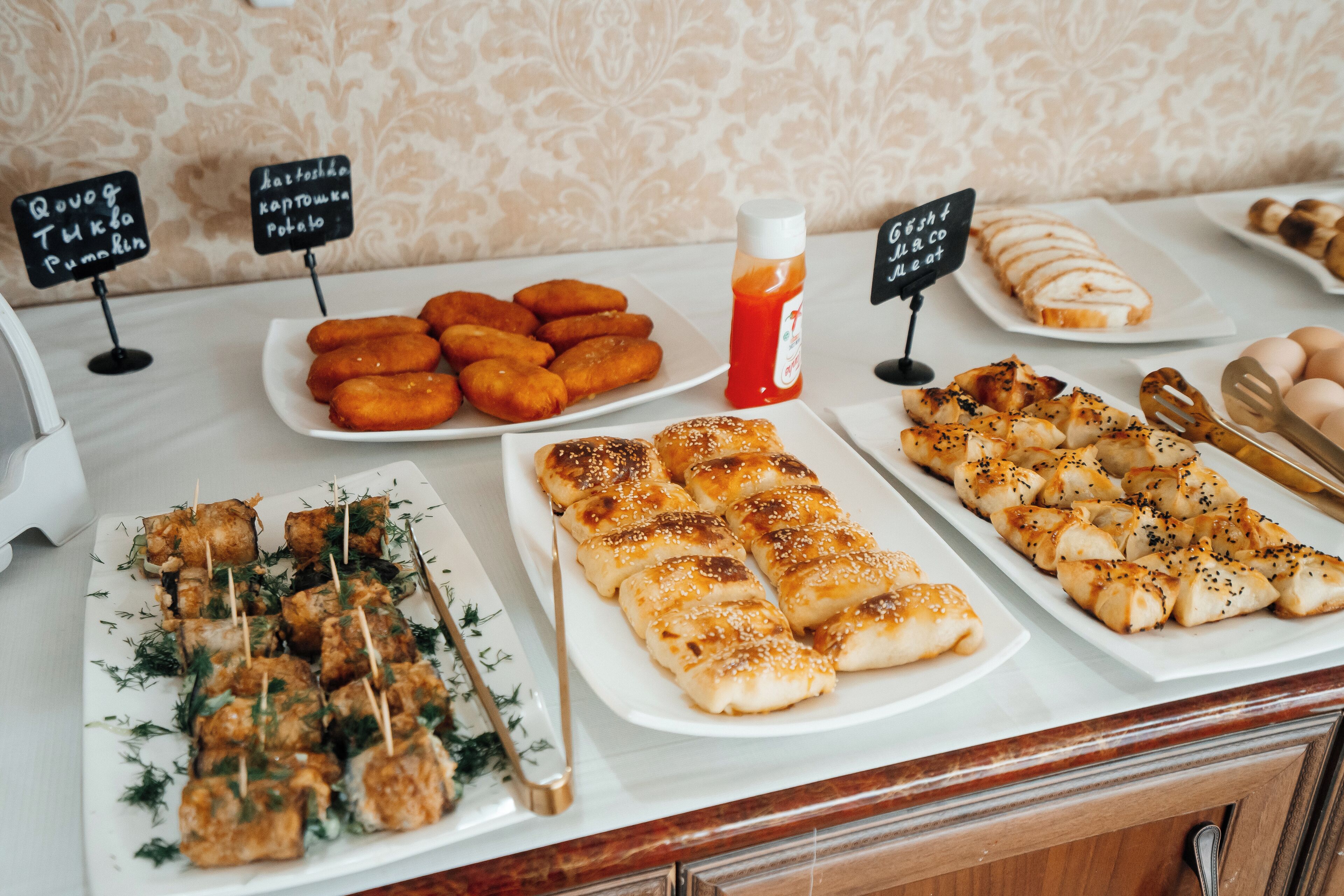 A buffet with various dishes including skewers, bread rolls, and pastries.