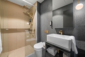 A modern bathroom with a glass-enclosed shower, a white sink, and a large mirror.