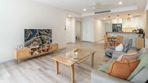 A modern living room with a glass-top coffee table, a sofa, and a dining area with a table and chairs.