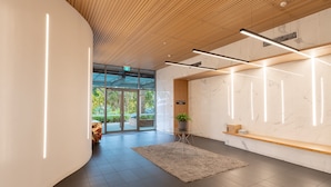 A modern reception area with a curved wall, a wooden ceiling, and a marble wall with a built-in shelf.