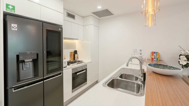 A modern kitchen with stainless steel appliances, a water dispenser, a sink, and a unique pendant light.
