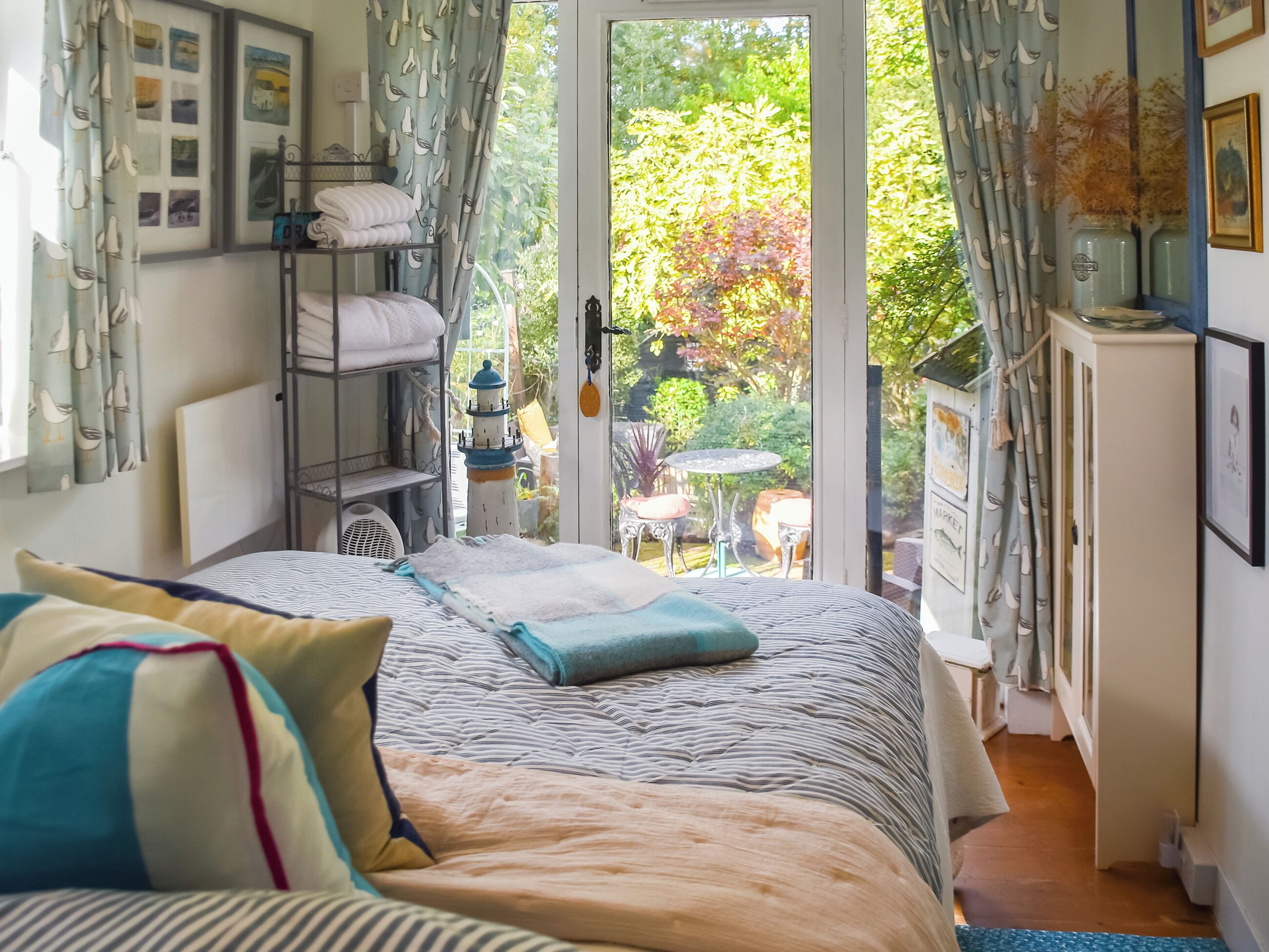 A bedroom with a bed, a bunk bed, a small table, and a view of the garden through a glass door.