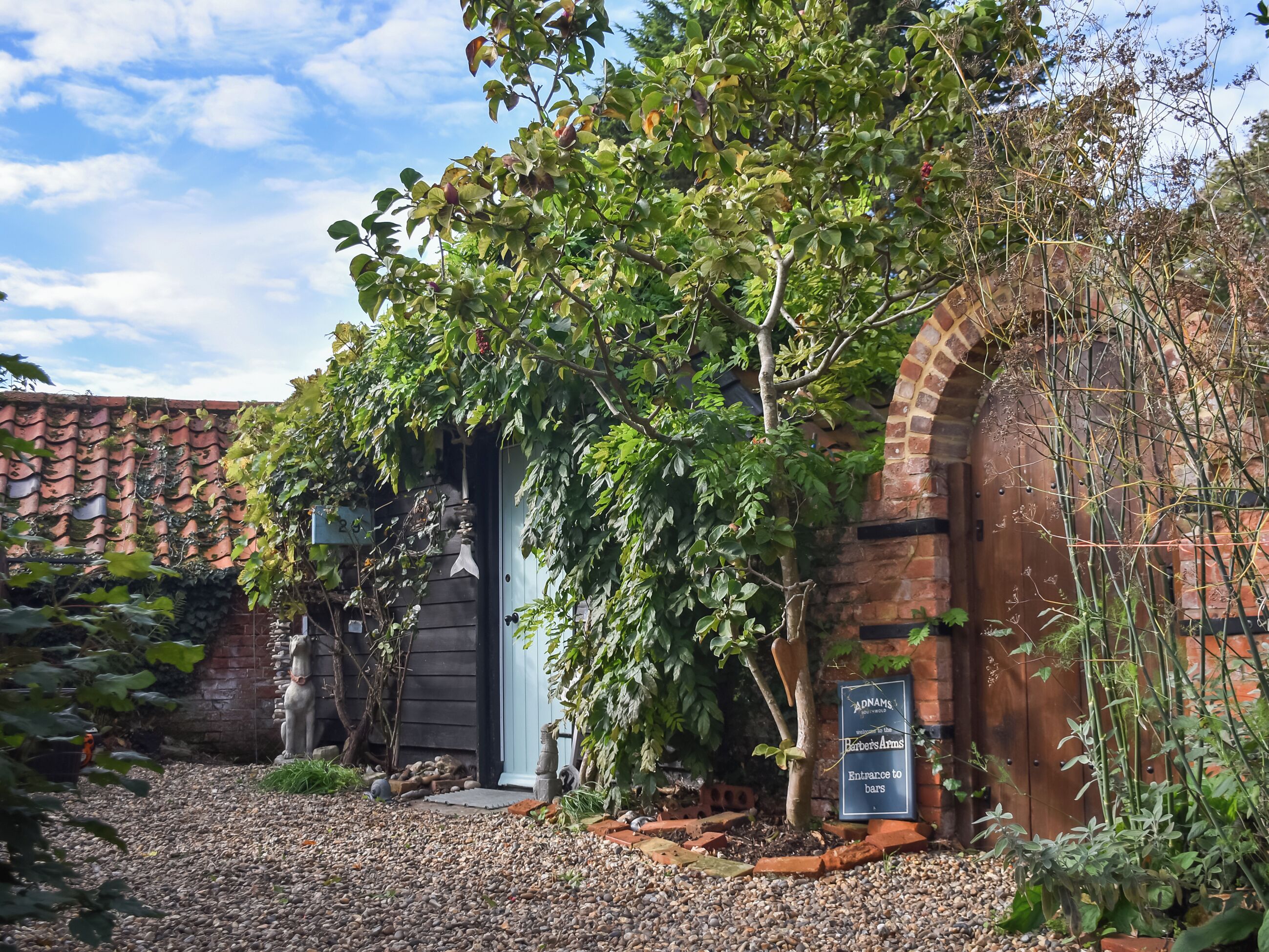 A rustic building with a brick archway, a wooden door, and a sign indicating an entrance to bars.