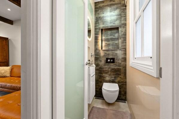 Un baño moderno con cabina de ducha de vidrio, inodoro blanco y lavabo con espejo.