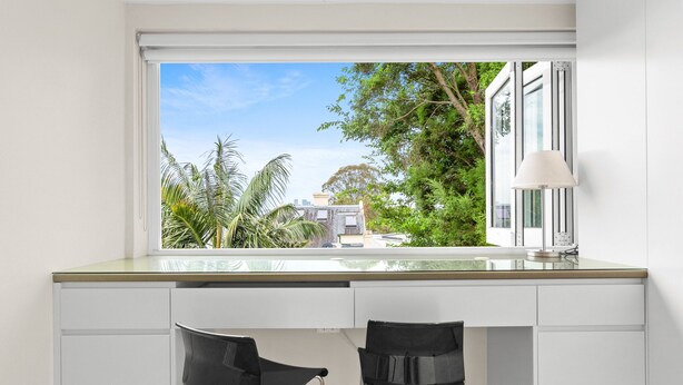 A modern kitchen with a large window, two black chairs, and a white countertop. - Elegant 1-bed With Study by Balmain Wharf (Sydney)