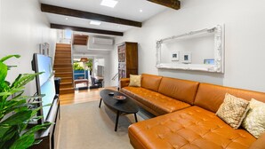 A modern living room with a leather sofa, a coffee table, and a large mirror on the wall. - Elegant 1-bed With Study by Balmain Wharf (Sydney)