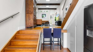 A modern kitchen with wooden flooring, a built-in refrigerator, and a dining area with two chairs. - Elegant 1-bed With Study by Balmain Wharf (Sydney)