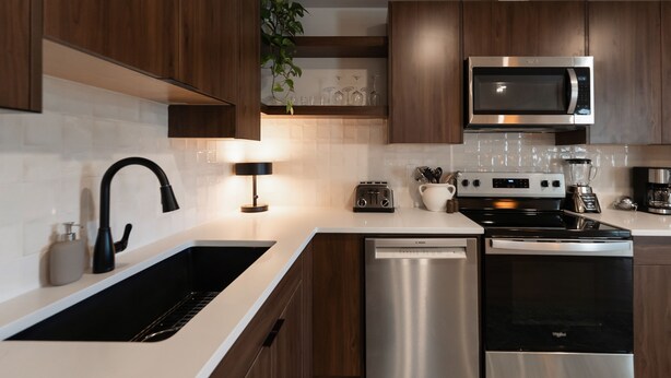 A modern kitchen with wooden cabinets, a stainless steel dishwasher, a microwave, a stove, and a coffee maker. - Nordic Suite W | Private, Fenced Yard, Outdoor Patio w/ Fire-Table, A/C, Laundry (Lethbridge)